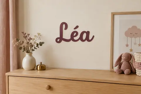 Lettrage prénom en vinyle sur un mur ivoire près d’une commode en bois clair